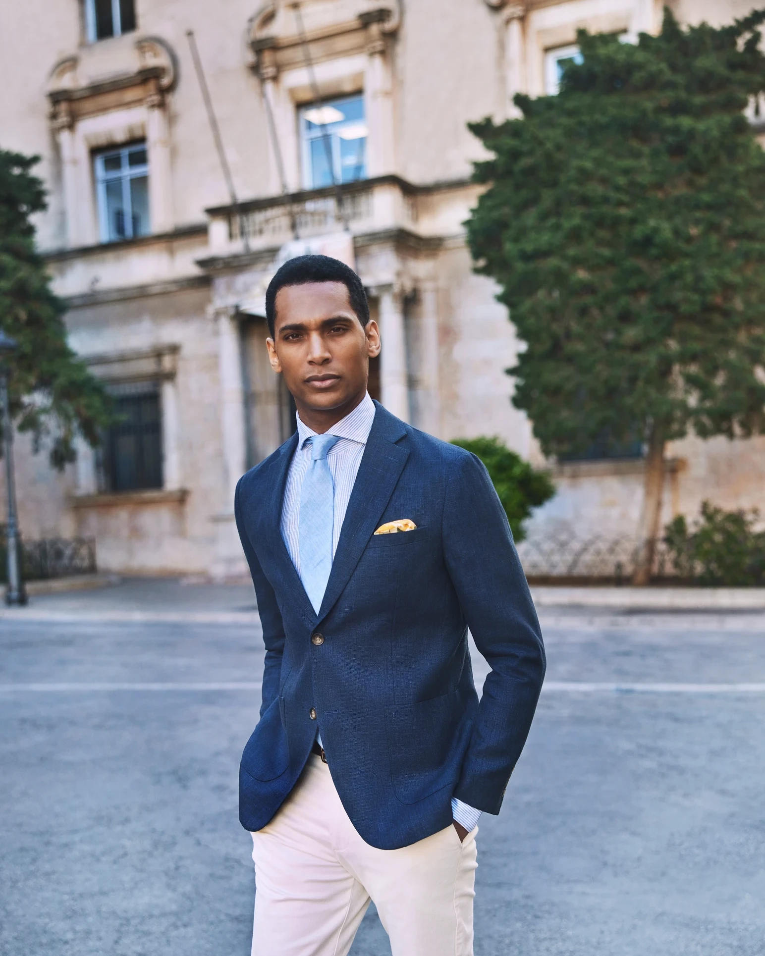 Male fashion model in a navy suit photographed on a city street
