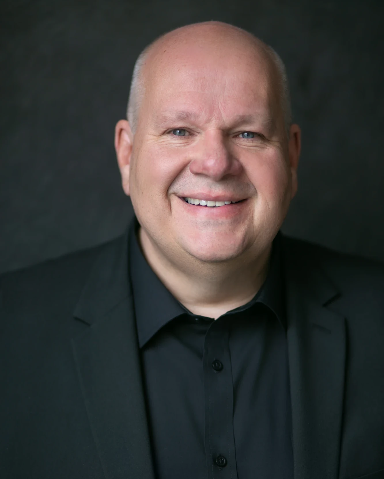 Retouched corporate headshot of a male executive in a dark jacket