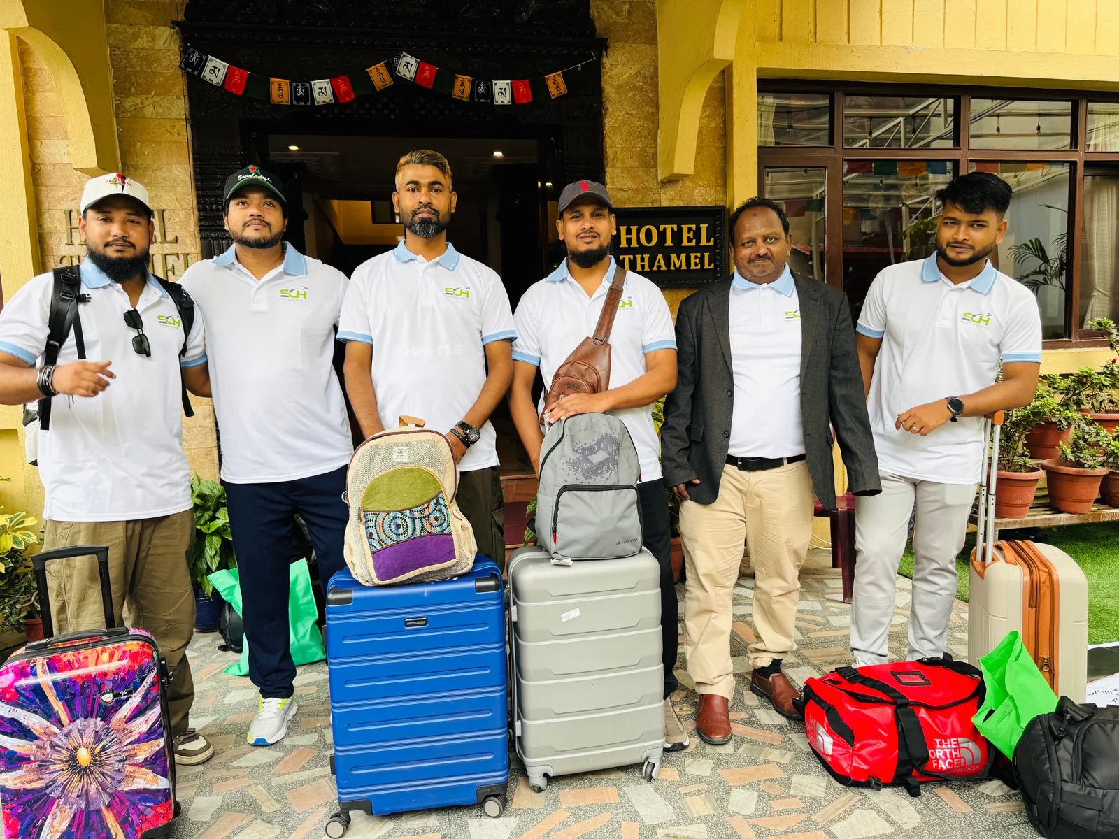 Studio Click House team in matching polo shirts with luggage outside Hotel Thamel