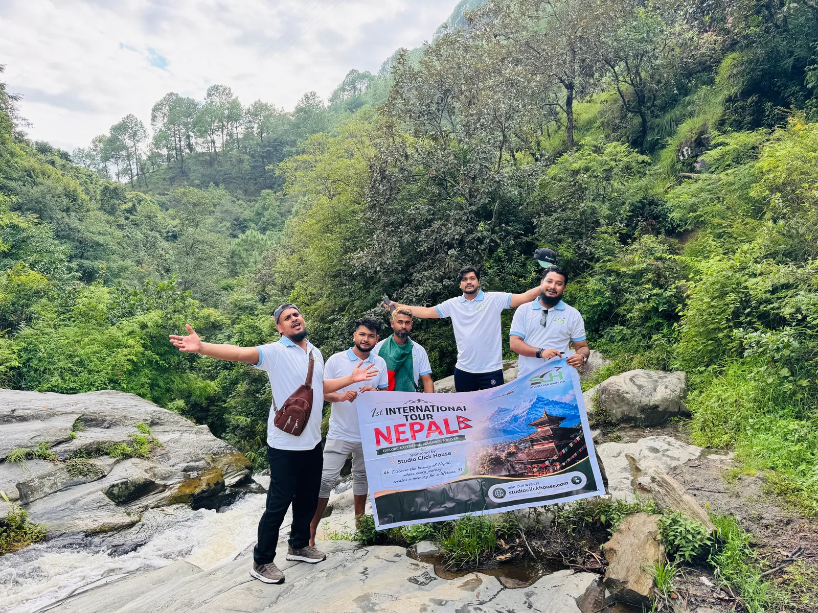 Studio Click House team with expedition banner by mountain waterfall