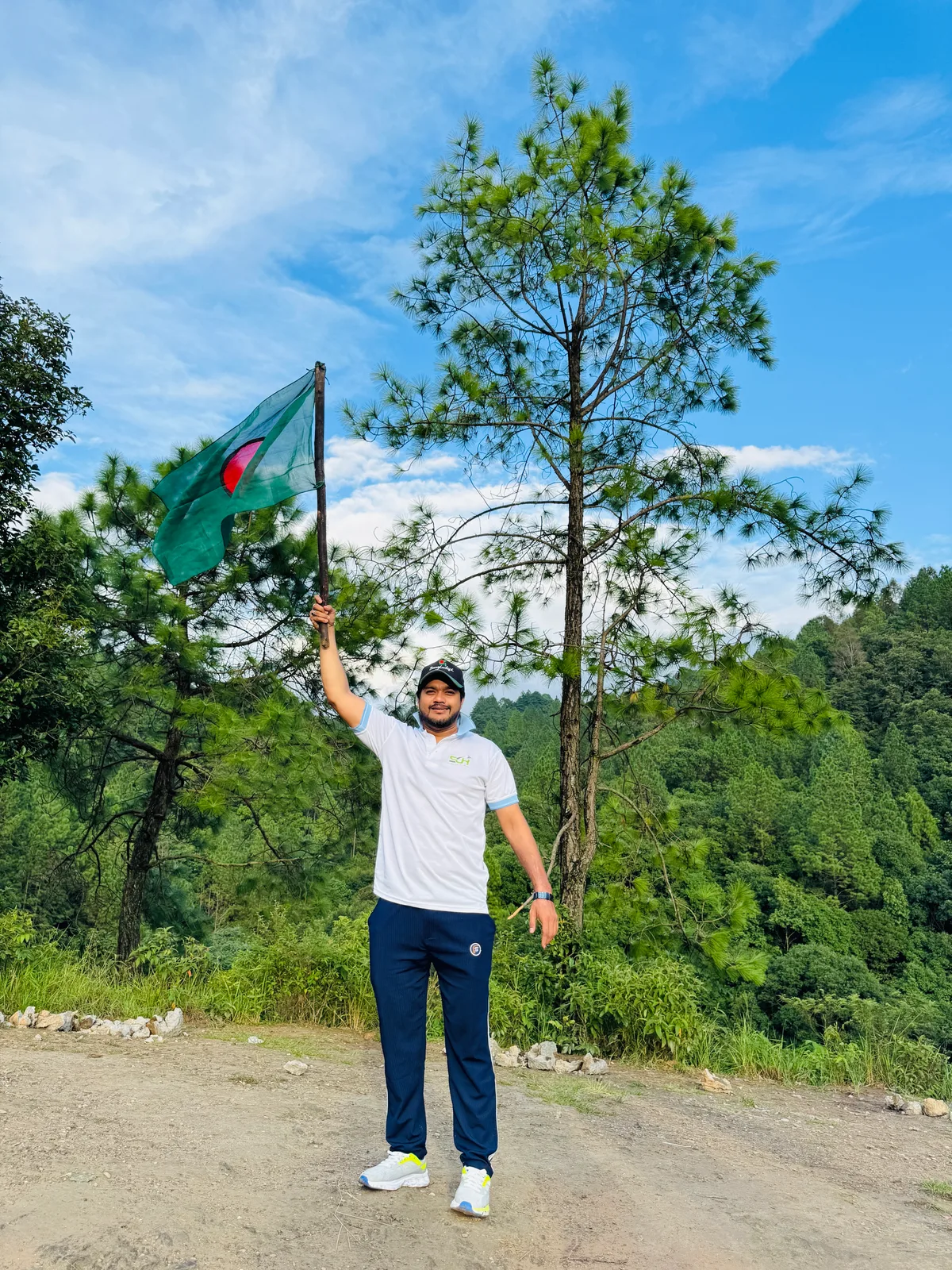 Team member waving Bangladesh flag against clear Himalayan skies