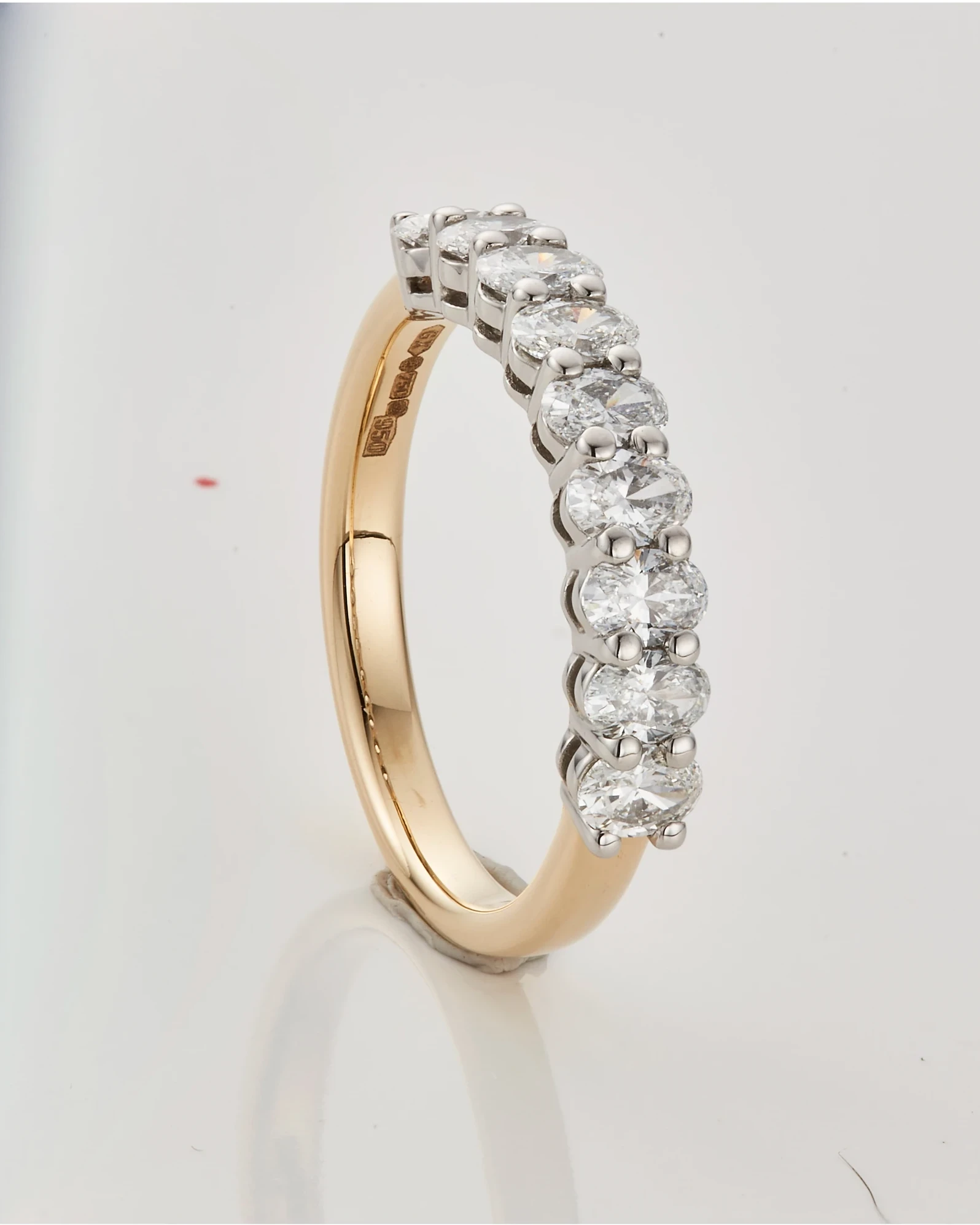Gold and diamond eternity band before retouching, with a marked studio background