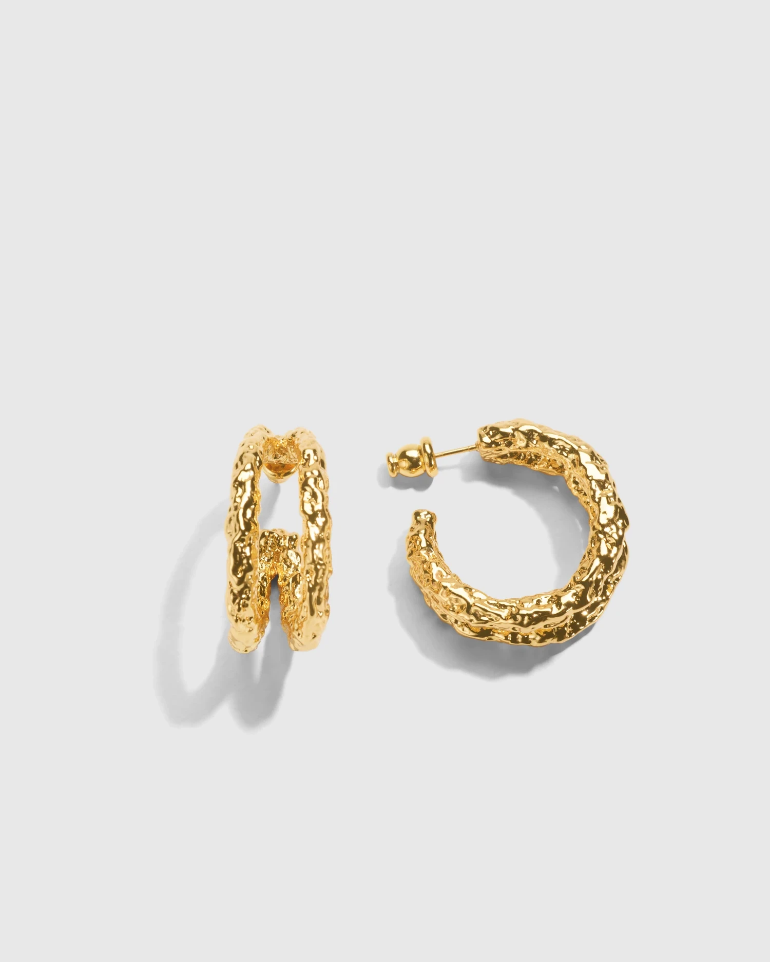Retouched sculptural gold earrings on a light background