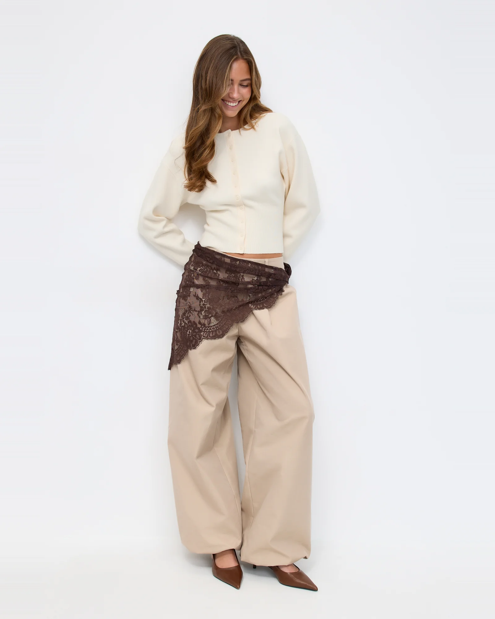 Fashion model in complete editorial outfit with tailored trousers and lace wrap